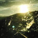 A photograph of the sun seen through a dirty, scraped glass.