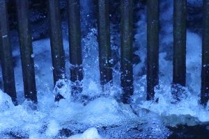 A close-up photograph of water rushing between metal bars.