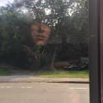 A photograph of a girl reflected in a window.
