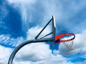 A photograph of a swaying basketball hoop against an interesting sky.