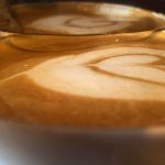 A close-up photograph of a hot drink reflected in a butter knife.