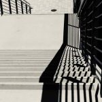 A photograph of the harsh shadows of a railing on some steps.